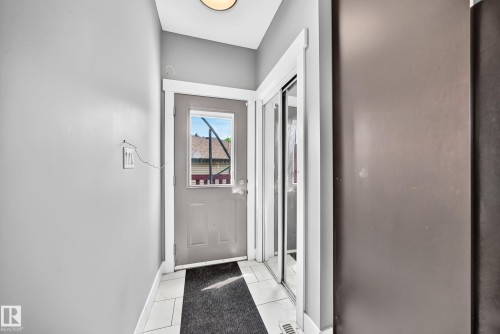 Entryway featuring a grey door with an upper window pane, white trim, and a built-in closet with mirrored sliding doors - 12730 118 Street Nw, Edmonton, AB 