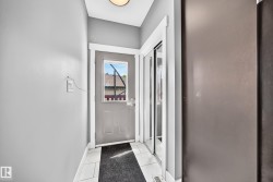 Entryway featuring a grey door with an upper window pane, white trim, and a built-in closet with mirrored sliding doors - 