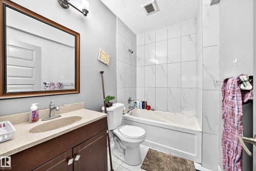 Vanity with an integrated sink, framed mirror, and a bathtub with tile surround - 12730 118 Street Nw, Edmonton, AB 