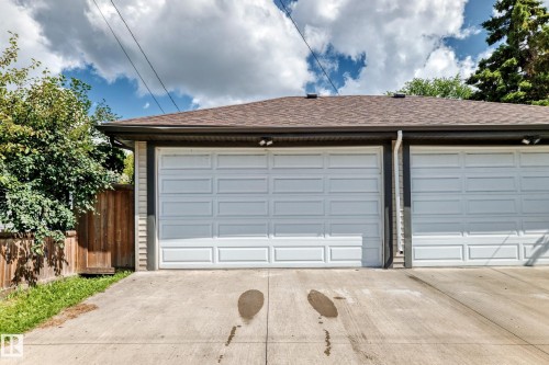 Two white paneled garage doors, asphalt shingle roof, and concrete driveway - 12730 118 Street Nw, Edmonton, AB 