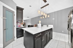 Kitchen island with a light-toned countertop, dark cabinetry, and pendant lighting - 