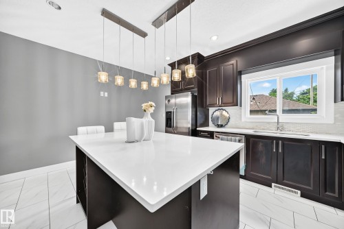 Kitchen featuring dark wood cabinetry, white countertops, tile flooring, stainless steel appliances, and recessed lighting - 12730 118 Street Nw, Edmonton, AB 