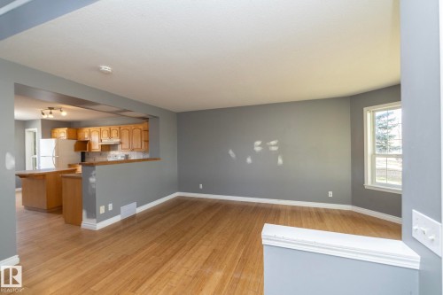 Wood-finish flooring throughout, light gray wall finishes, kitchen features wood cabinetry, white appliances, and track lighting - 137 Michigan Street, Devon, AB 