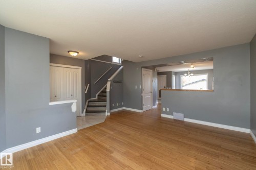 Hardwood-finish flooring, staircase with white risers, white trim, and a pass-through window opening - 137 Michigan Street, Devon, AB 