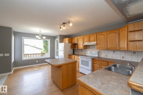 Kitchen featuring wood cabinetry, a center island, and a double basin sink - 137 Michigan Street, Devon, AB 