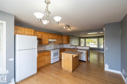 Kitchen featuring wood cabinetry, white appliances, a center island, and wood-finish flooring - 137 Michigan Street, Devon, AB 