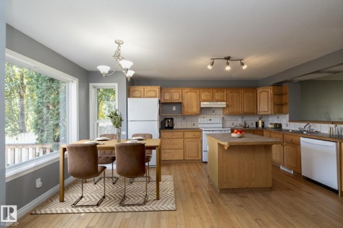 Wood-finish flooring throughout, white appliances, wood cabinetry, kitchen island, and a large picture window - 137 Michigan Street, Devon, AB 