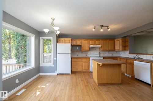 Kitchen featuring wood-finish cabinetry, a central island, and white appliances - 137 Michigan Street, Devon, AB 
