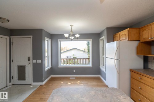Wood-finish flooring with tile entry, white trim, and a built-in refrigerator - 137 Michigan Street, Devon, AB 