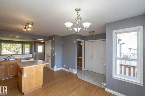 Wood-finish flooring, central kitchen island, white trim, track lighting, and a chandelier - 137 Michigan Street, Devon, AB 