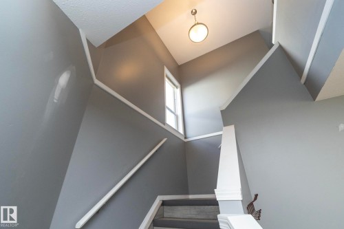 Stairway featuring gray walls, white trim, a fixed window, and an overhead light fixture - 137 Michigan Street, Devon, AB 