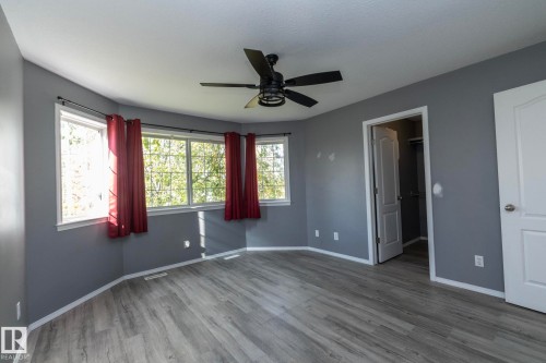 Wood-finish flooring, bay window with multiple panes, ceiling fan light fixture, and white trim - 137 Michigan Street, Devon, AB 