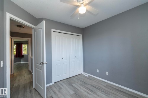 Gray-toned walls, wood-finish flooring, white bi-fold closet doors, and a ceiling fan with integrated lighting - 137 Michigan Street, Devon, AB 