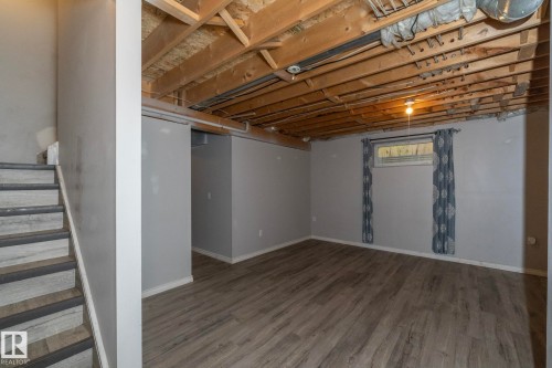Wood-finish flooring with light gray walls, exposed ceiling joists, and a window - 137 Michigan Street, Devon, AB 