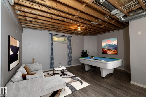 Open concept lower level featuring wood-finish flooring, exposed ceiling joists, and a partial window - 137 Michigan Street, Devon, AB 