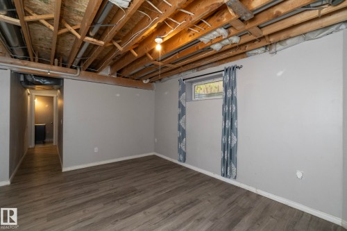 Wood-finish flooring with a neutral wall color, exposed ceiling joists, and a window for natural light - 137 Michigan Street, Devon, AB 
