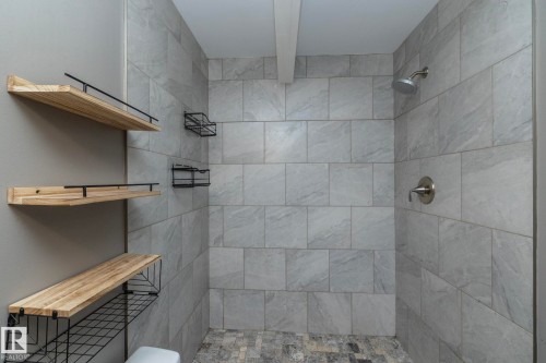 Shower with large format gray wall tiling, brushed nickel shower fixtures, and gray mosaic floor tiling - 137 Michigan Street, Devon, AB 