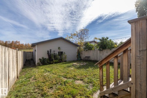 Expansive grassy yard with a detached structure, wood privacy fencing, and wood-finish stairs - 137 Michigan Street, Devon, AB 