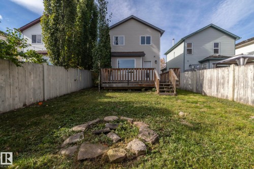Expansive backyard featuring a wood deck with stairs, a privacy fence, and a stone-lined fire pit - 137 Michigan Street, Devon, AB 