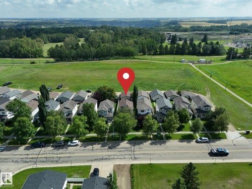 Residential street with sidewalks and mature trees, bordered by expansive green fields and distant wooded areas - 137 Michigan Street, Devon, AB 