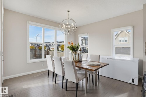 Bright interior with light wood-finish flooring, a contemporary spherical chandelier, and multiple windows with white trim - 9448 228 Street Nw, Edmonton, AB 