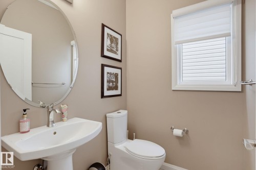 Pedestal sink with chrome faucet, oval wall mirror, and window with privacy blinds - 9448 228 Street Nw, Edmonton, AB 