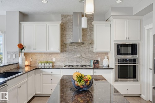 White cabinetry, dark stone countertops, stainless steel appliances, mosaic tile backsplash, and recessed lighting - 9448 228 Street Nw, Edmonton, AB 
