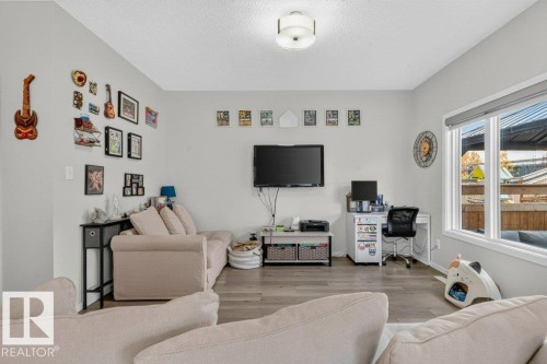 Recessed ceiling lighting, wood-finish flooring, light neutral wall tones, and a large window with roller shades - 1020 Daniels Loop Sw, Edmonton, AB 