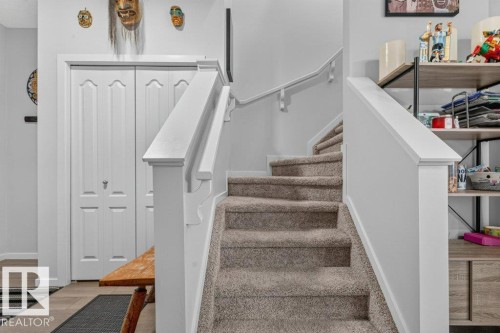 Carpeted staircase with white painted balustrades and handrails - 1020 Daniels Loop Sw, Edmonton, AB 