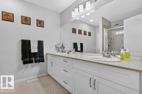 Double vanity with undermount sinks, white cabinetry, chrome hardware, and a framed shower with a glass enclosure - 1020 Daniels Loop Sw, Edmonton, AB 