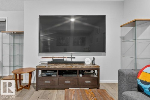 Wall-mounted display, wood-finish flooring, light-toned wall paint, built-in display cases, and a media console with drawers - 1020 Daniels Loop Sw, Edmonton, AB 