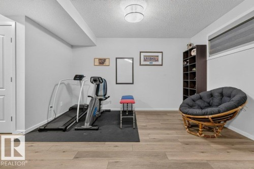Wood-finish flooring, recessed ceiling beam, neutral wall paint, and a built-in shelving unit - 1020 Daniels Loop Sw, Edmonton, AB 