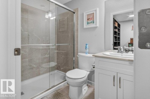 Walk-in shower with clear glass enclosure, gray tile surround, and built-in shower niche - 1020 Daniels Loop Sw, Edmonton, AB 