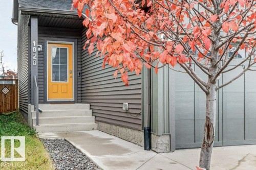 Fiber cement siding exterior with a bright yellow front door, concrete porch steps, and an attached garage with a panel door - 1020 Daniels Loop Sw, Edmonton, AB 