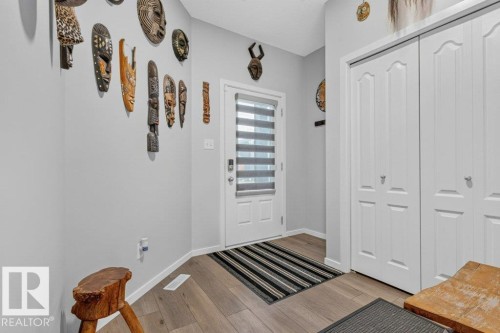 Entryway featuring wood-finish flooring, a white door with integrated window blinds, and white bi-fold closet doors - 1020 Daniels Loop Sw, Edmonton, AB 