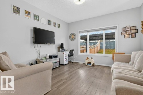 Spacious room with wood-finish flooring, light grey wall paint, and a large window - 1020 Daniels Loop Sw, Edmonton, AB 