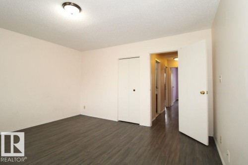 White ceramic toilet, vanity with wood-finish cabinetry, solid surface countertop, integrated sink, and wall-mounted mirror - 11393 22 Avenue Nw, Edmonton, AB 
