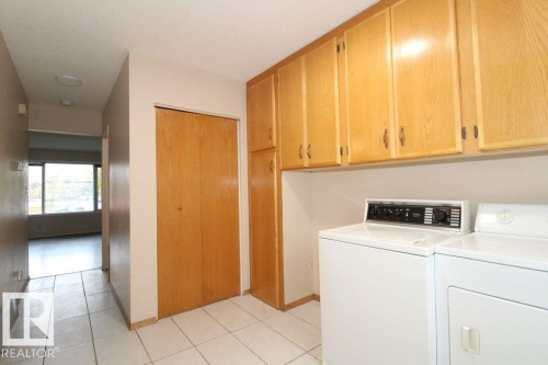 Laundry area with wood-finish cabinetry, tile flooring, and a built-in closet - 11393 22 Avenue Nw, Edmonton, AB 