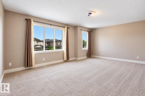 Expansive room featuring neutral-toned carpeting, multiple windows, and a flush-mount ceiling light fixture - 258 Albany Drive Nw, Edmonton, AB 