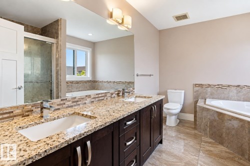Dual vanity with granite countertops, rich wood-finish cabinetry, and contemporary chrome fixtures - 258 Albany Drive Nw, Edmonton, AB 