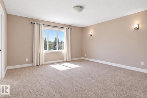 Neutral tone wall paint, wall-mounted sconce lighting, white trim, and a window with a neighborhood backdrop - 258 Albany Drive Nw, Edmonton, AB 