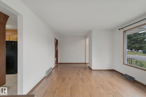 Hardwood flooring, painted white walls, wood trim, and a large window with exterior railing - 8424 70 Street Nw, Edmonton, AB 