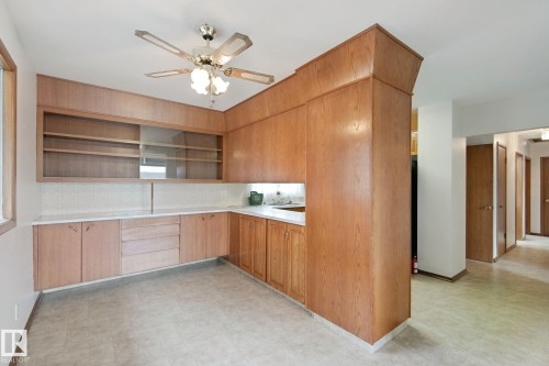 Built-in wood-finish cabinetry with open shelving and glass-front upper cabinets, integrated sink, and white countertop - 8424 70 Street Nw, Edmonton, AB 