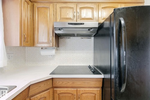 Warm wood cabinetry with arched details, a stainless steel range hood, and a black built-in refrigerator - 8424 70 Street Nw, Edmonton, AB 
