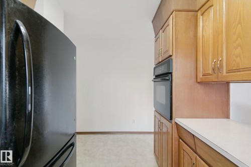 Built-in oven, wood-finish cabinetry, light-toned countertops, and hard surface flooring - 8424 70 Street Nw, Edmonton, AB 