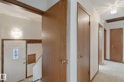 Entryway featuring a decorative glass panel door, built-in coat rack, and recessed staircase - 8424 70 Street Nw, Edmonton, AB 