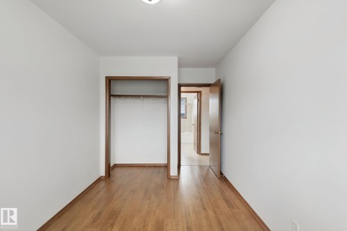 Hardwood flooring, painted walls, open closet with hanging rod, and a solid core interior door - 8424 70 Street Nw, Edmonton, AB 