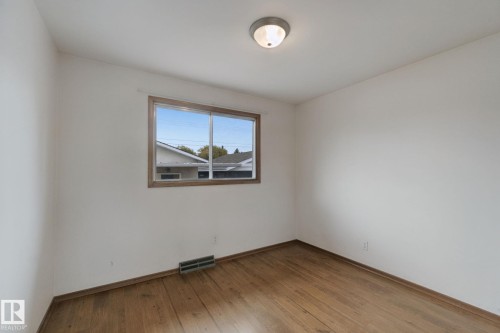 Wood-finish flooring, white walls, and a window with wood trim - 8424 70 Street Nw, Edmonton, AB 