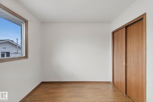 Wood-finish flooring, white walls, and a window with wood trim - 8424 70 Street Nw, Edmonton, AB 
