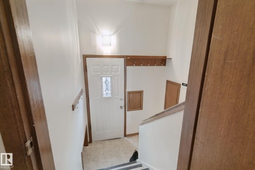 Entryway featuring a decorative transom door, tiled flooring, wood-finish trim, and a built-in coat rack - 8424 70 Street Nw, Edmonton, AB 
